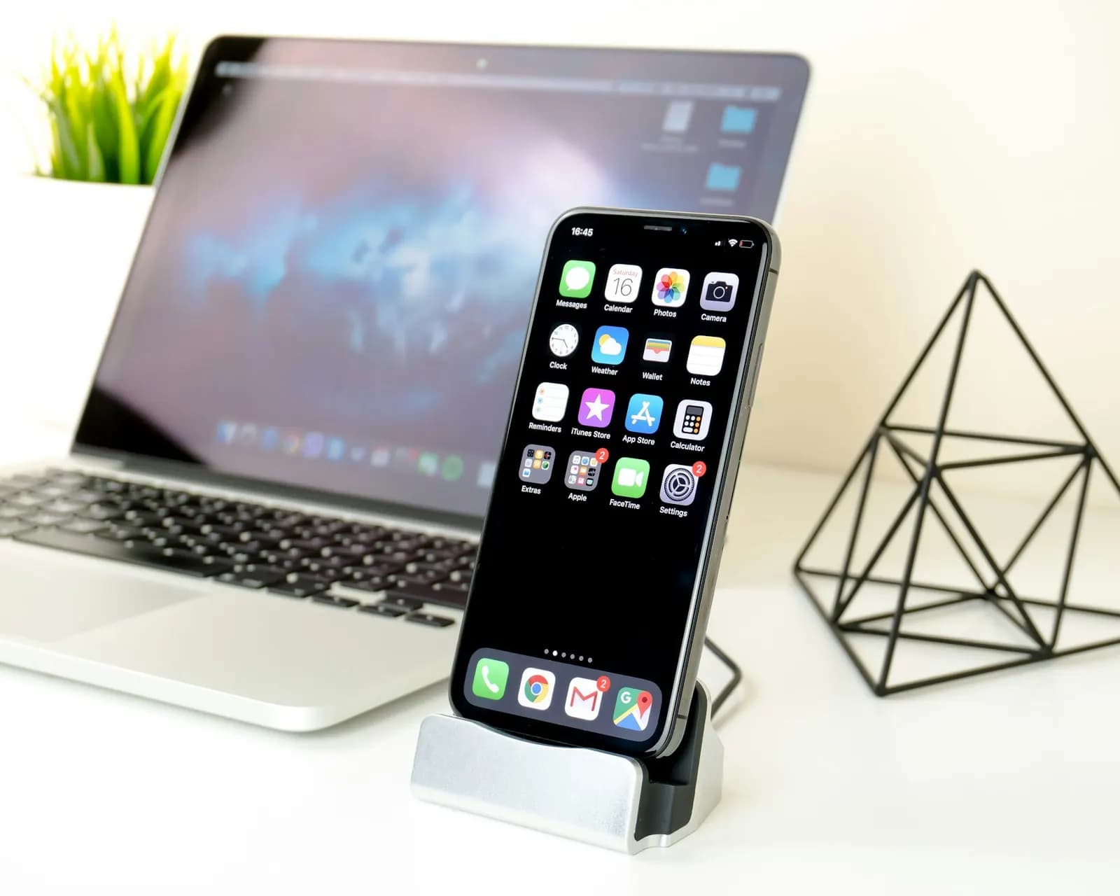 Masada dizüstü bilgisayarın önünde duran bir akıllı telefon