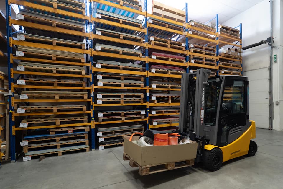 Paletli raflar arasında yük taşıyan forklift