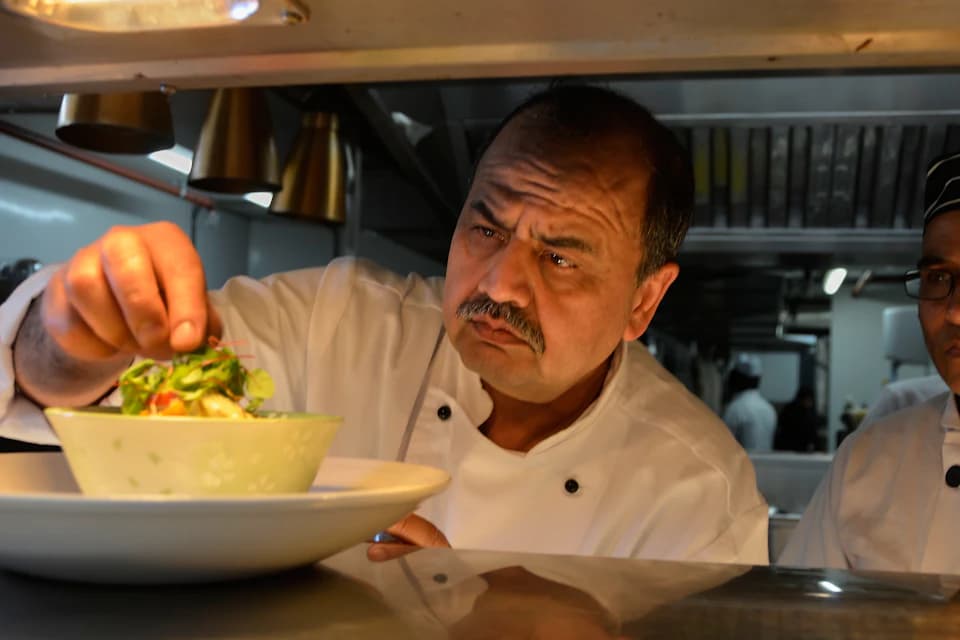 Restoran mutfağında servise çıkacak tabağı süsleyen aşçı